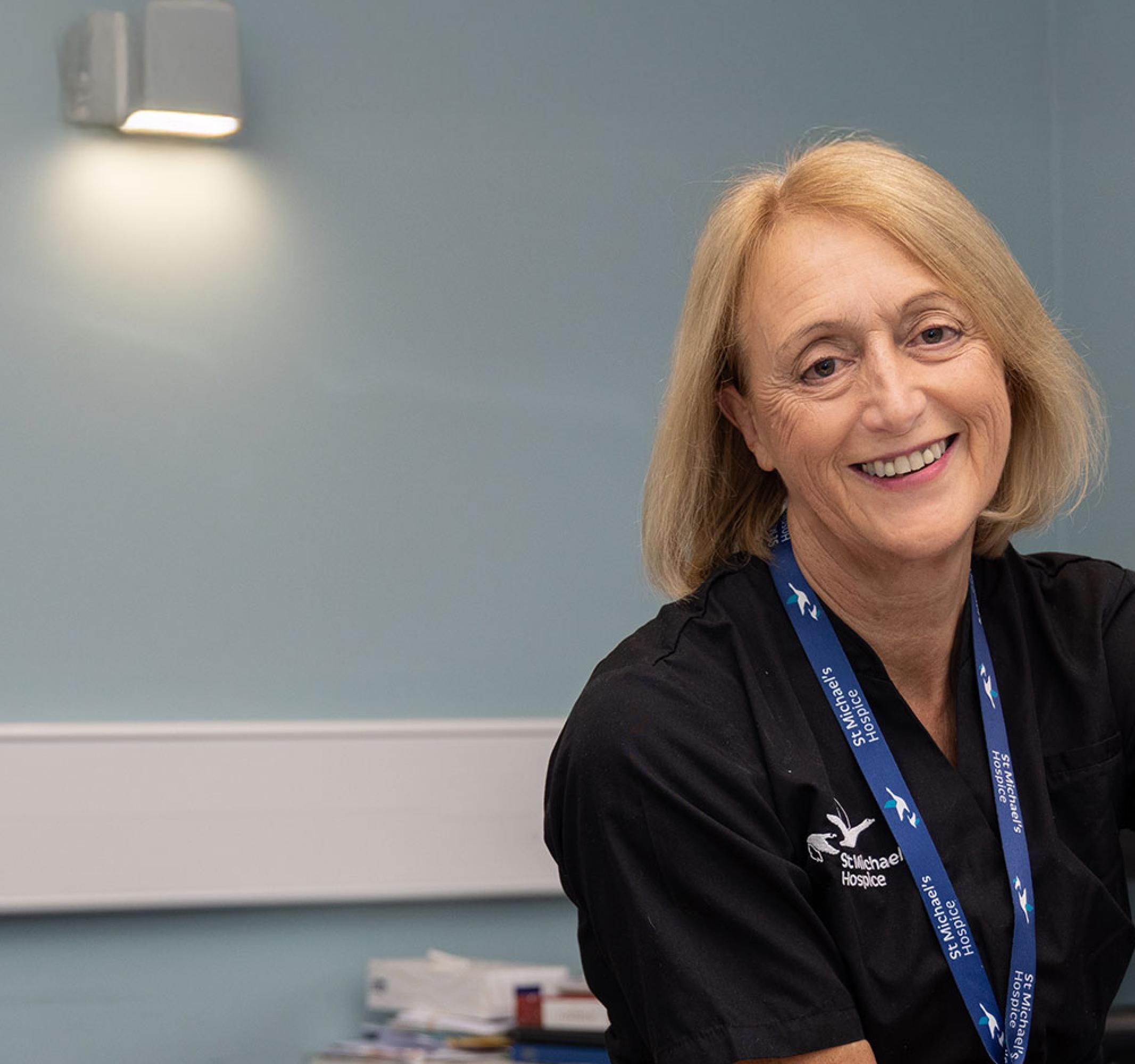 Smiling female healthcare professional examining a patient's foot in a clinic.