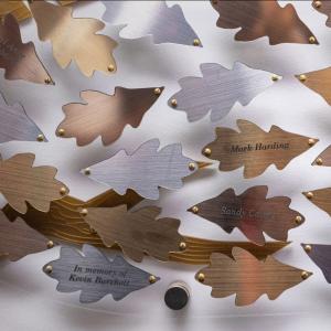 Person viewing a wall of metallic oak leaf plaques with etched names.