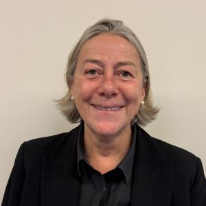 Smiling woman with gray hair in a black blazer.