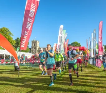 Runners participating in an outdoor race with colorful flags and a castle in the distance.