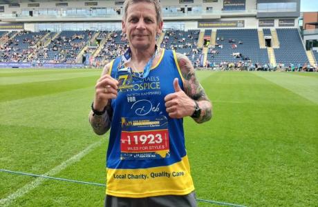 Darren standing in a stadium with a medal having completed a sporting event for st michaels