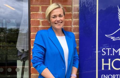 Elizabeth standing outside St Michaels Hospice wearing a bright blue blazer
