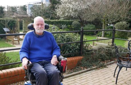 Simon outside the hospice wearing a bright blue jumper