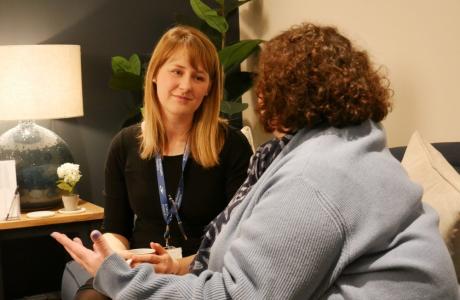 2 women wearing lanyards talk to each other in an office