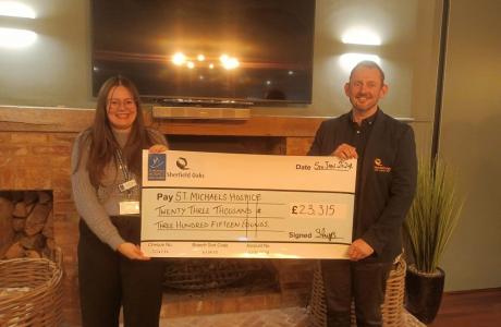 Two smiling people holding a large novelty check for €2,510 indoors.