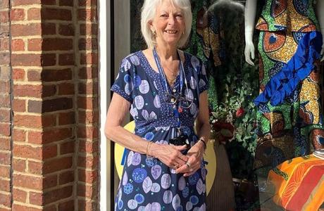 Shirley: woman with grey hair wearing purple dress and lanyard standing outside hospice