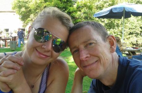 Smiling woman in sunglasses and man in a bright outdoor garden.