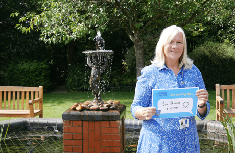Tracy standing outside the hospice holding a memorial plaque for her husband