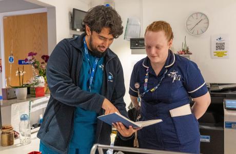 Healthcare workers, a man and woman, reviewing a patient chart together.