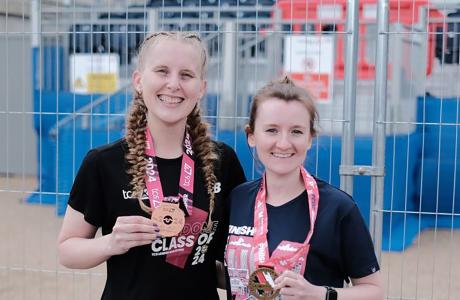 Two female runners with medals for the London marathon.