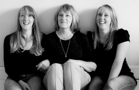 Black and white photograph of a smiling mother and her two daughters.