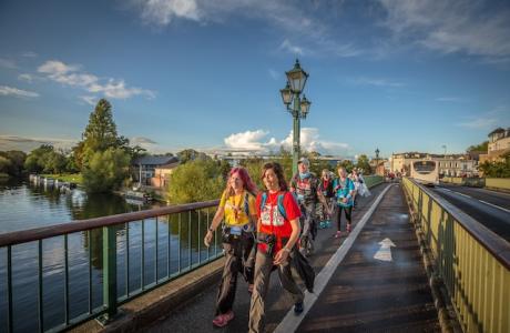 Two people walking across a bridge with a blue sky in the background