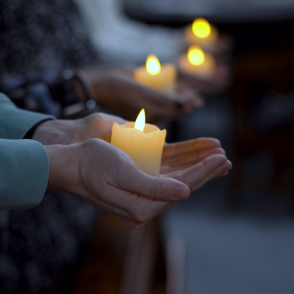 Image of hands holding lit candles
