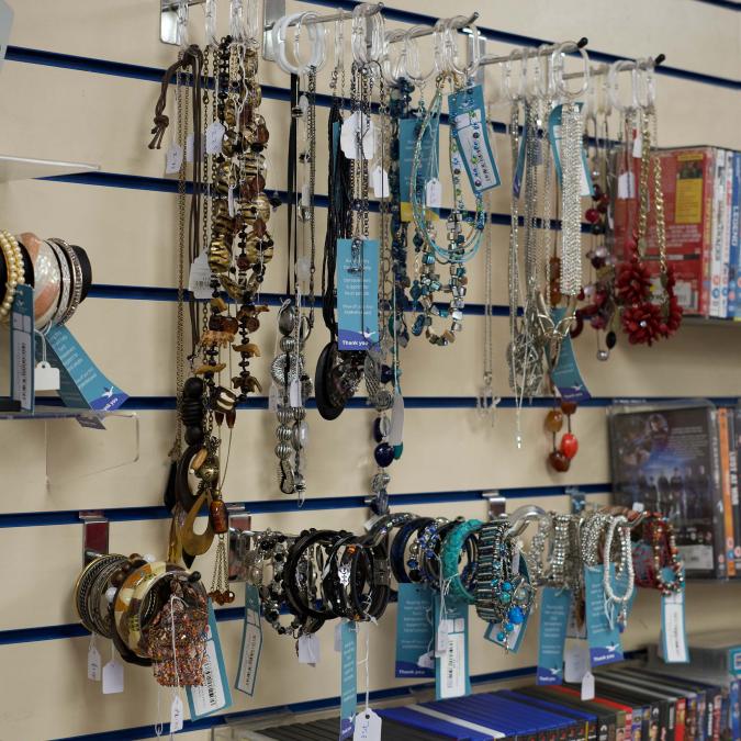 Jewelry display wall with various necklaces and bracelets on hooks.