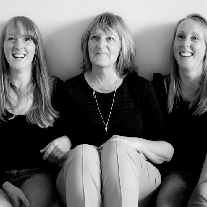 Black and white photograph of a smiling mother and her two daughters.