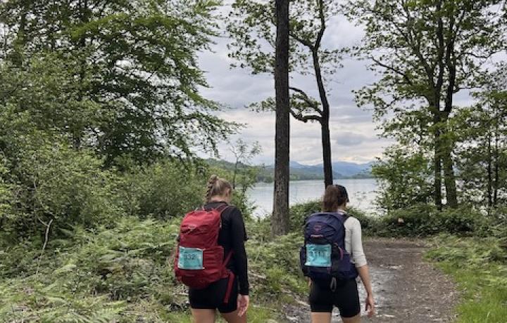 Two people in walking gear walking in the woods taking on the Lake District Challenge