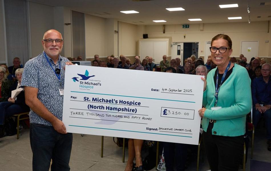 Man and woman holding a large check for St. Michael's Hospice, £1,350.00.