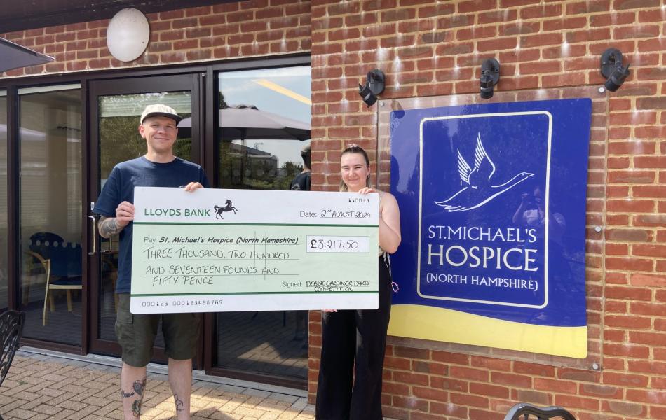 Man and woman hold a large donation check for St. Michael's Hospice.