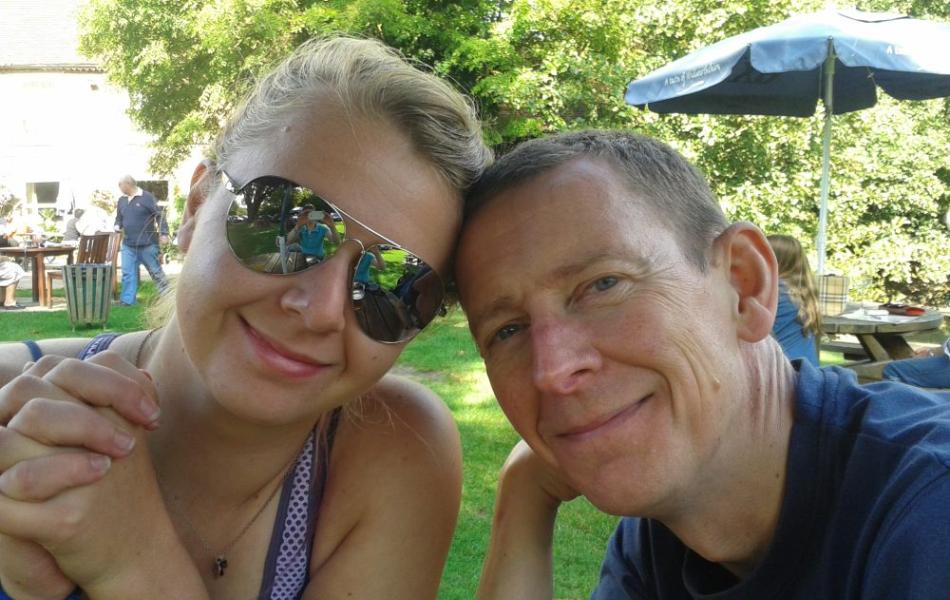 Smiling woman in sunglasses and man in a bright outdoor garden.