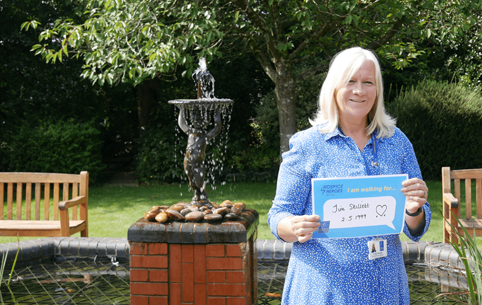 Tracy standing outside the hospice holding a memorial plaque for her husband