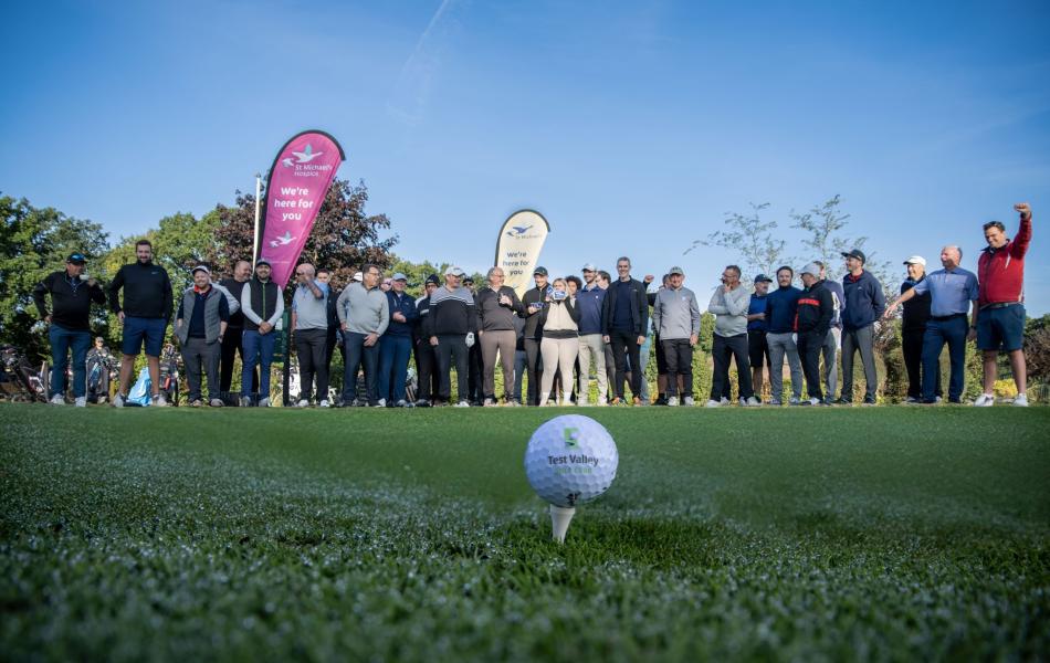 Golfers on charity day with gold flag and hole in foreground