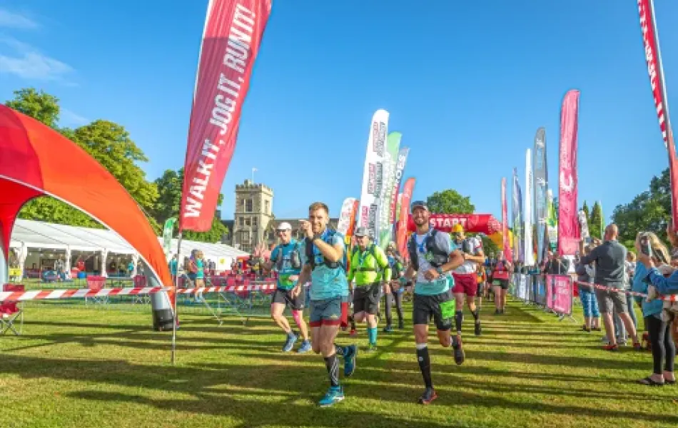 Runners participating in an outdoor race with colorful flags and a castle in the distance.