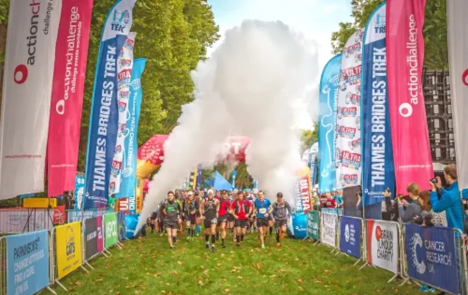Runners emerge from smoke at the start of a Thames Bridges Trek.