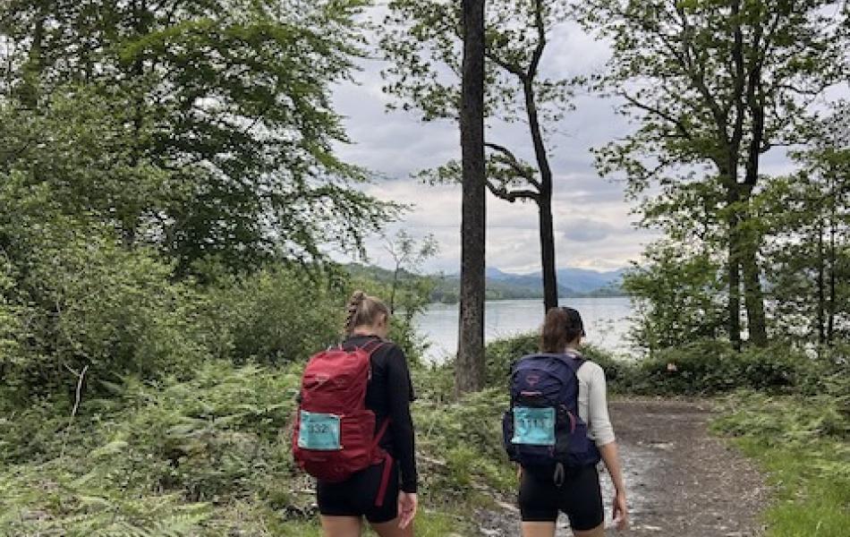 Two people in walking gear walking in the woods taking on the Lake District Challenge