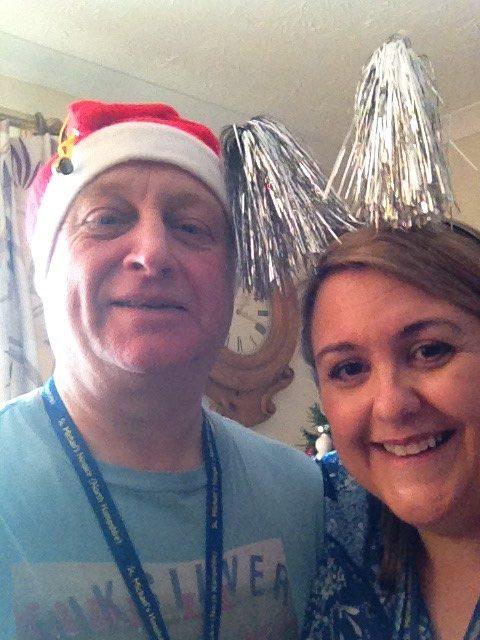 Steve and Nicola Volunteering at the hospice. Steve wears a santa hat and Nicola wears a tinsel headband.