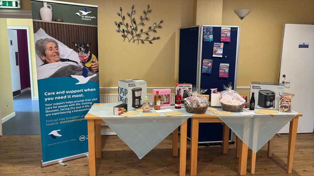 Room with a care services banner and tables filled with gift baskets and prizes.