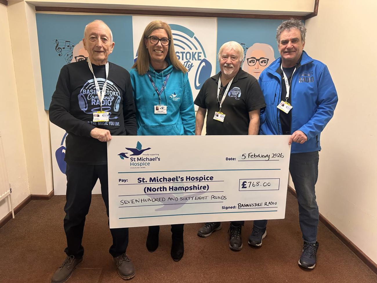 Four smiling adults hold a giant check for St Michael's Hospice.