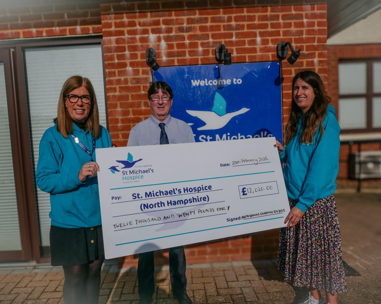 Three people holding a large charity cheque.