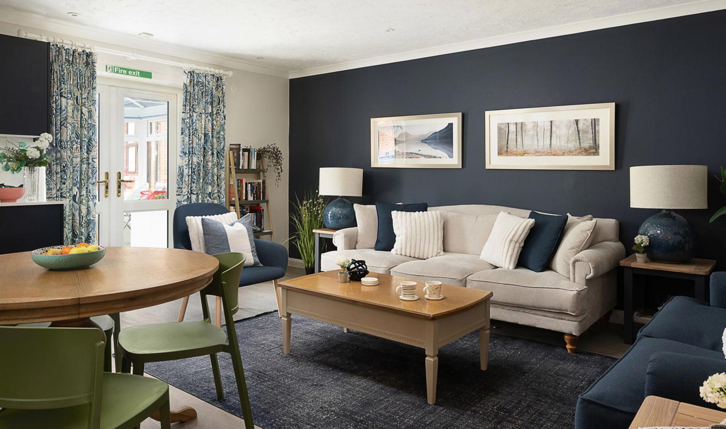 Modern room with a beige sofa, blue armchairs, and a wooden dining table.