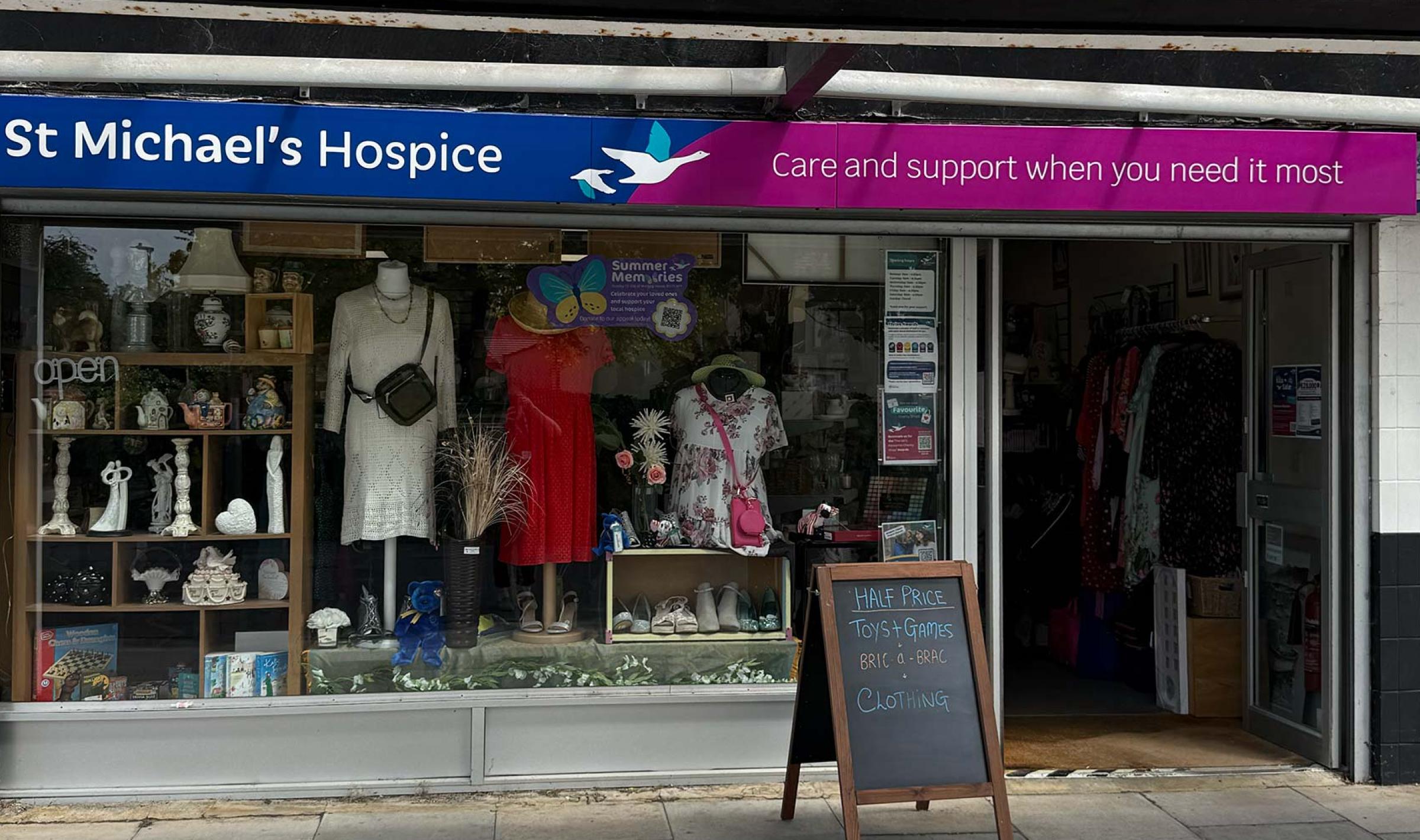 St Michael's Hospice charity shop storefront with a blue sign and window display.