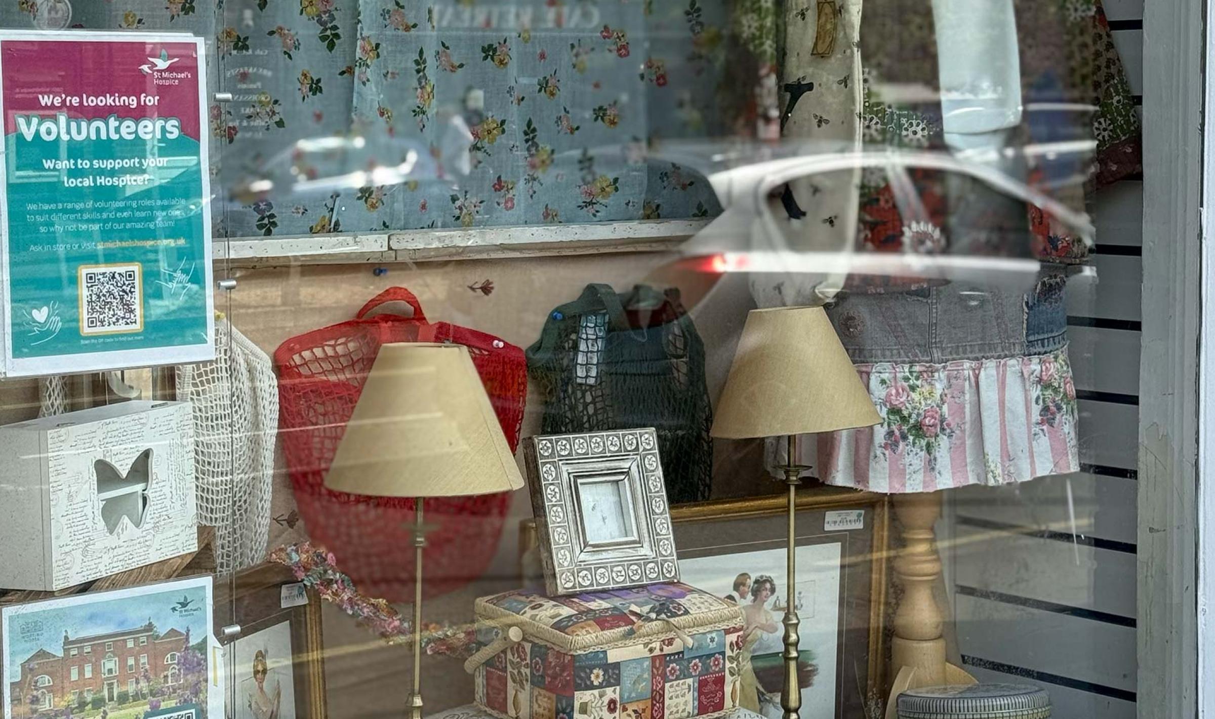 Shop window display featuring lamps, handbags, and clothing on a mannequin.