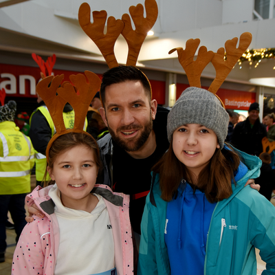 A family smiling at camera wearing reindeer antlers