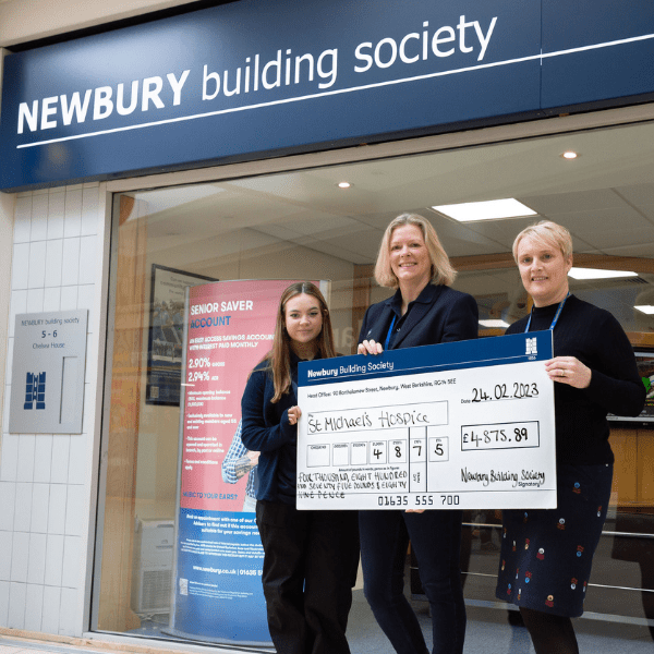Two members of staff from Newbury Building Society presenting us with a giant cheque outside their branch