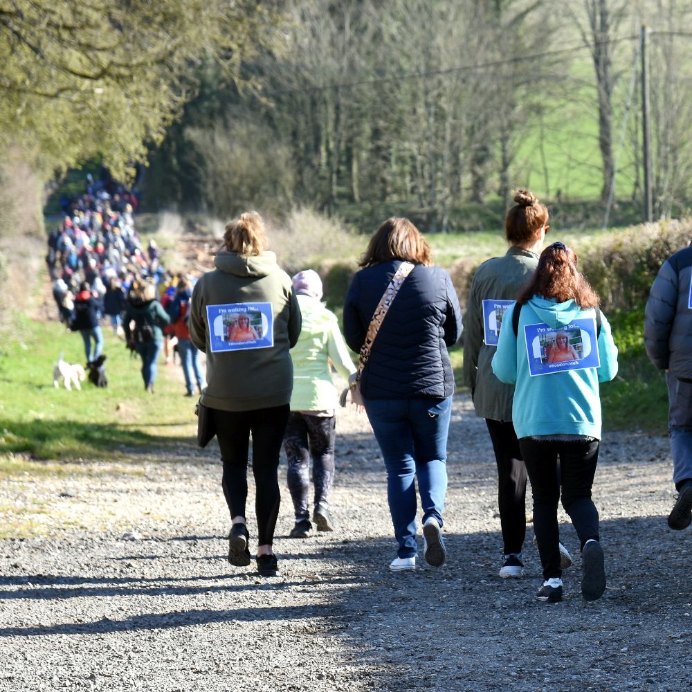 Image of a huge crowd of people walking through the countryside into a wooded area