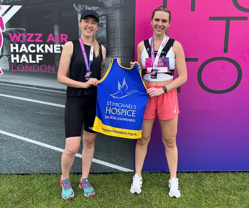 Lauren and Megan stood together, both holding a St. Michael's Hospice running vest