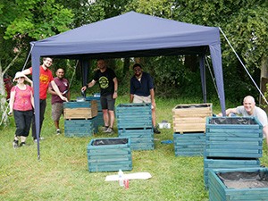 Staff from virgin media int he garden painting sunflower planters under a gazeebo