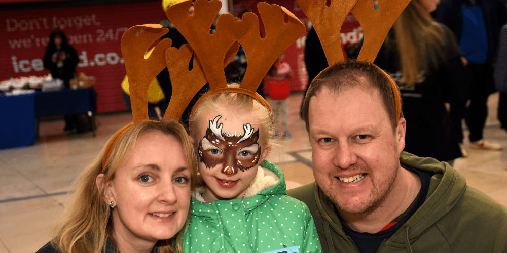 Image of Charlotte and her family wearing reindeer antlers. They're all smiling att he camera