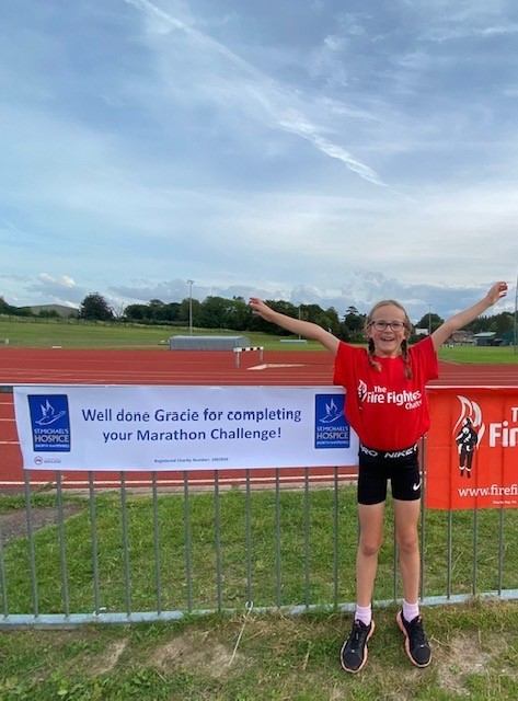 Image of a child cheering next to a St. Michael's Hospice sign