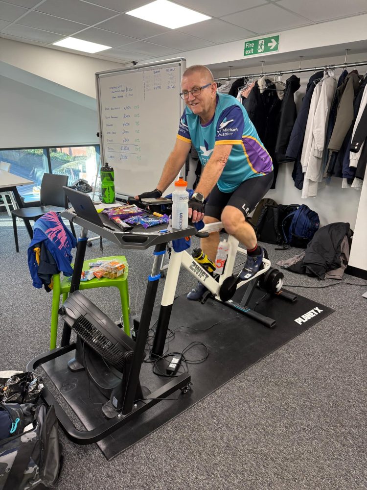 Photograph of Kevin wearing a St. Michael's Hospice top while riding on a static bike