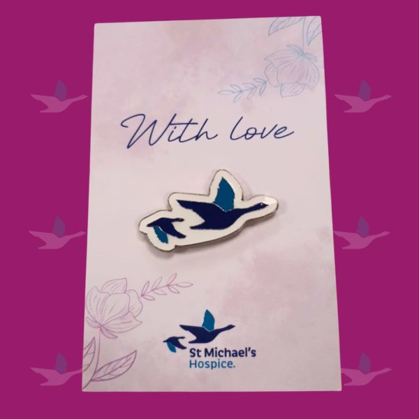 Goose pin badge on a decorative backing card.