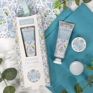 Photograph of the William Morris Lodden Hand and Lip Care set on a eucalyptus and blue floral background