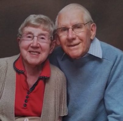 Photograph of Margaret and Ted cuddled together smiling at he camera